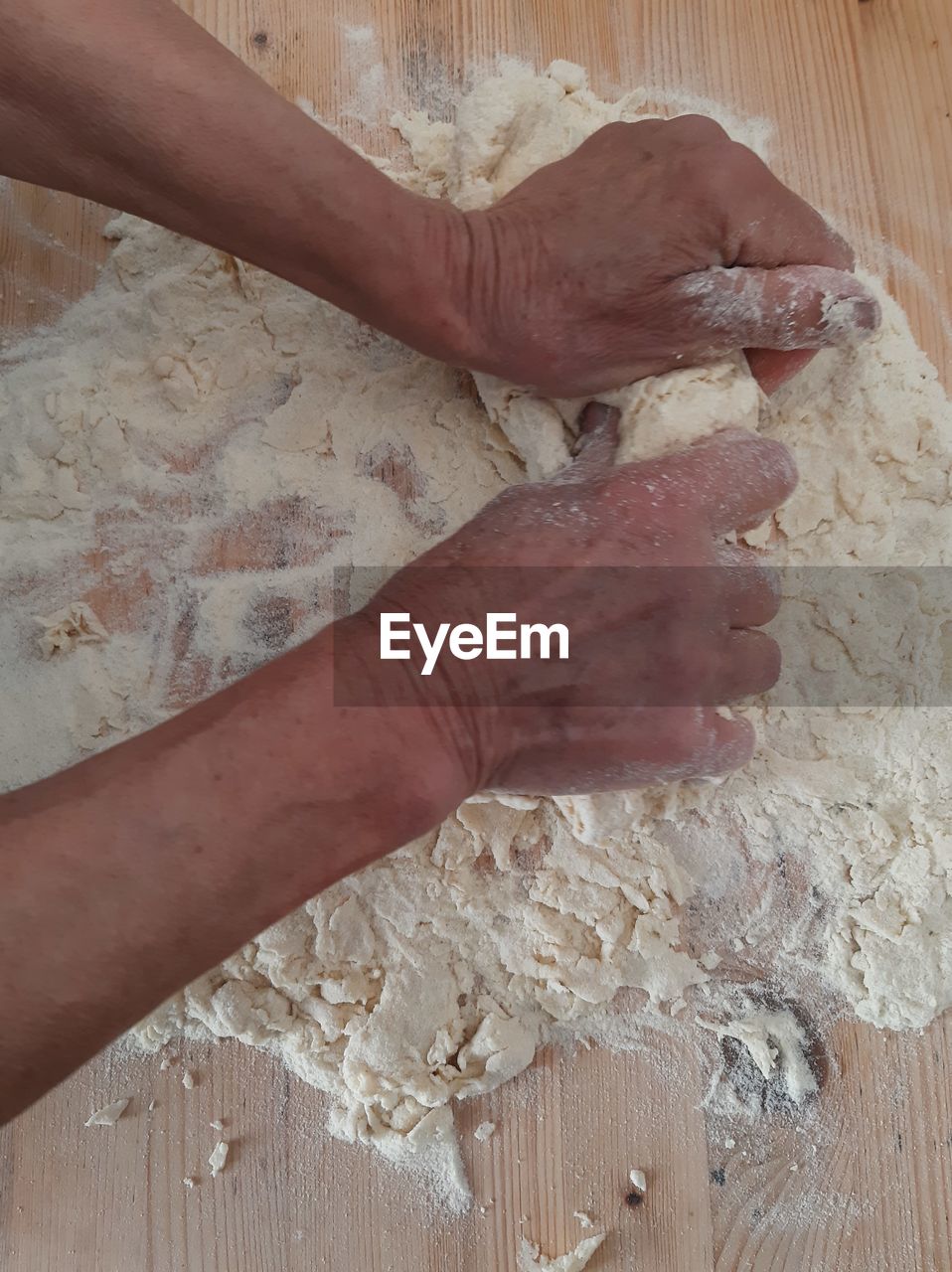 HIGH ANGLE VIEW OF PERSON PREPARING FOOD ON WOODEN FLOOR