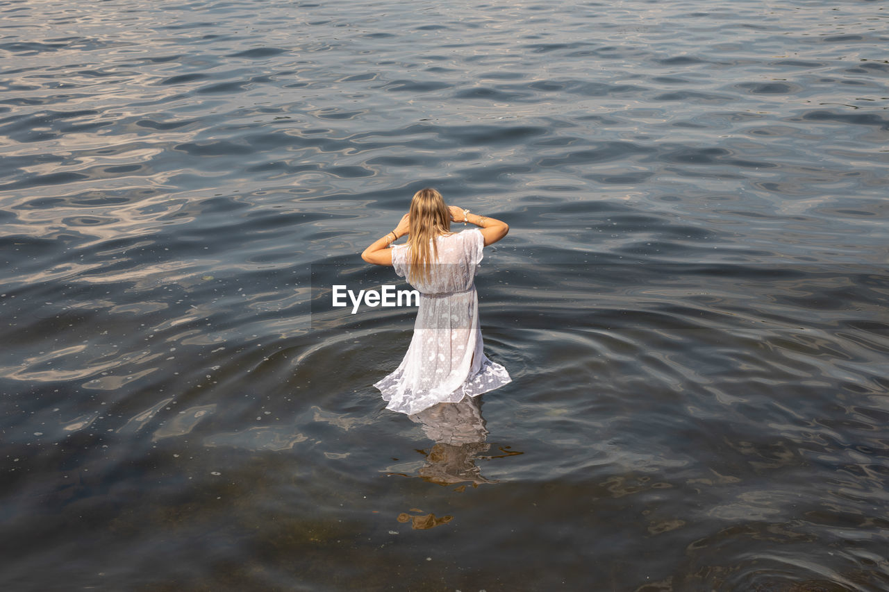 REAR VIEW OF WOMAN STANDING ON SEA