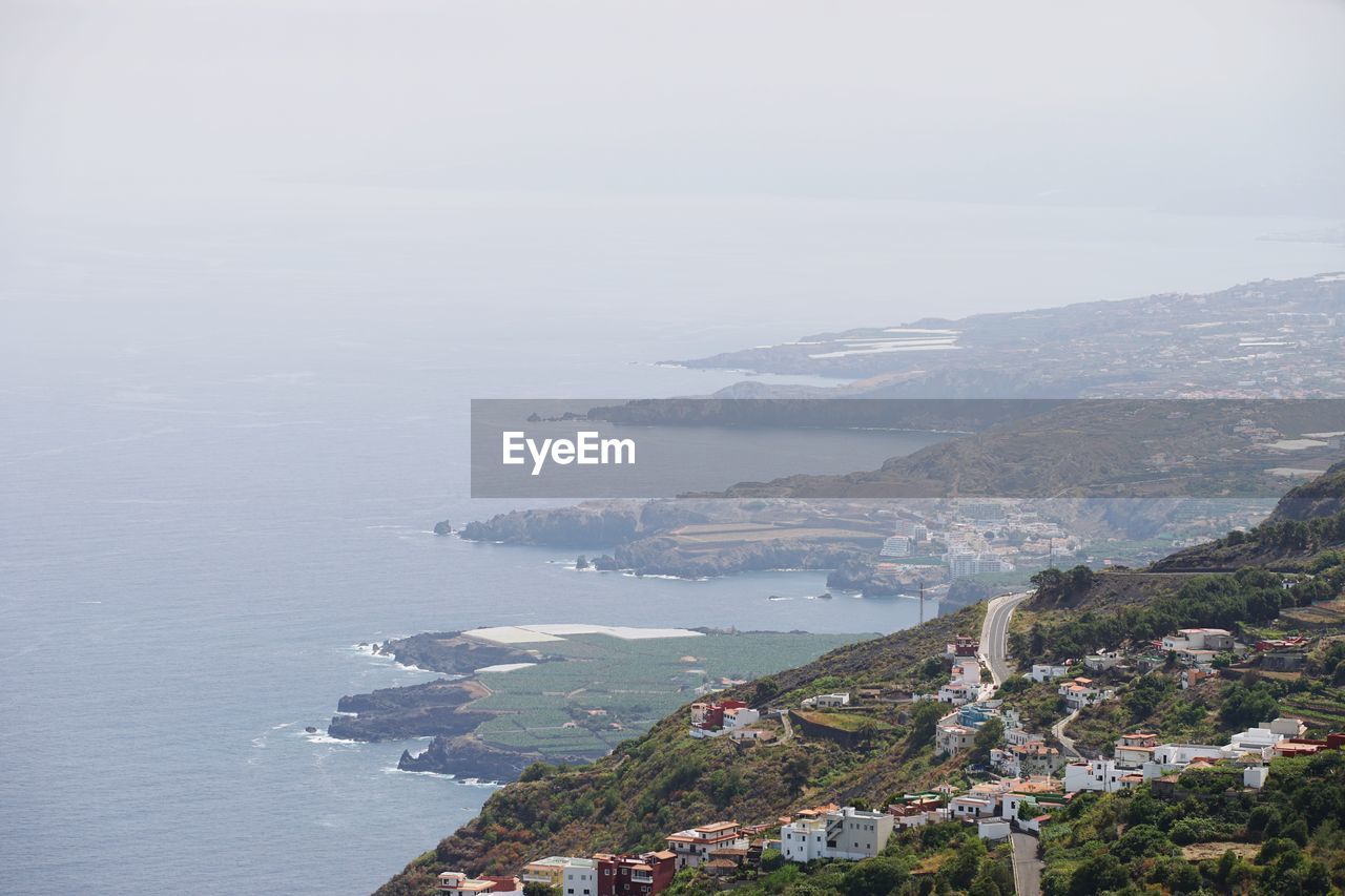 HIGH ANGLE VIEW OF SEA BY BUILDINGS AGAINST SKY