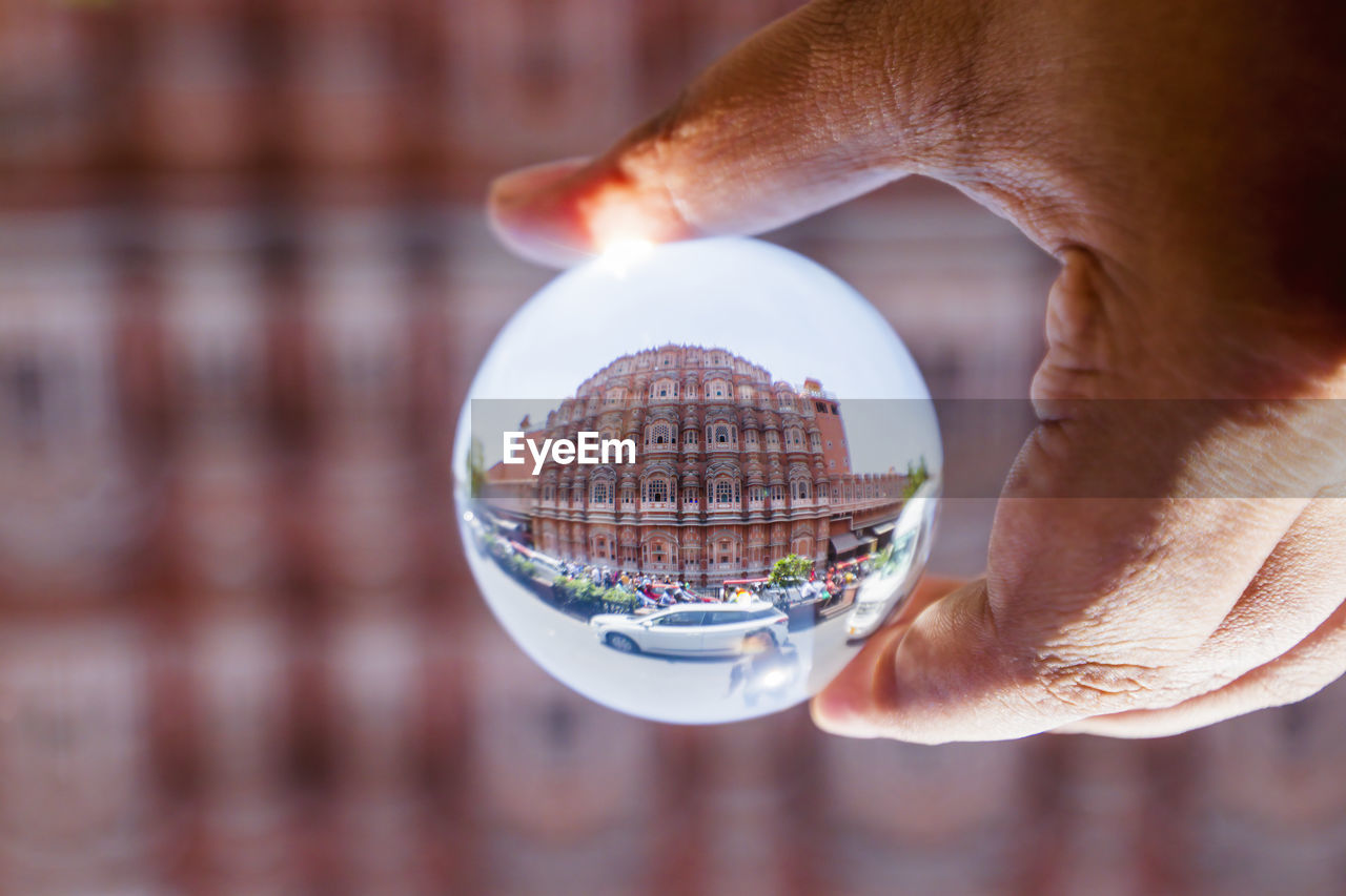 hand, holding, close-up, one person, sphere, adult, crystal ball, architecture, building exterior, focus on foreground, men, reflection, business, nature, technology, finger, globe - man made object, city, glass, outdoors, ball, built structure