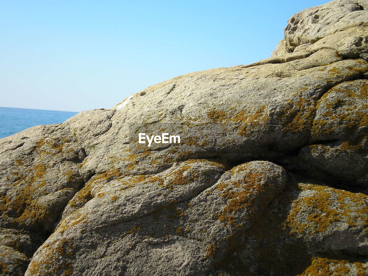LOW ANGLE VIEW OF ROCK FORMATION AGAINST SEA