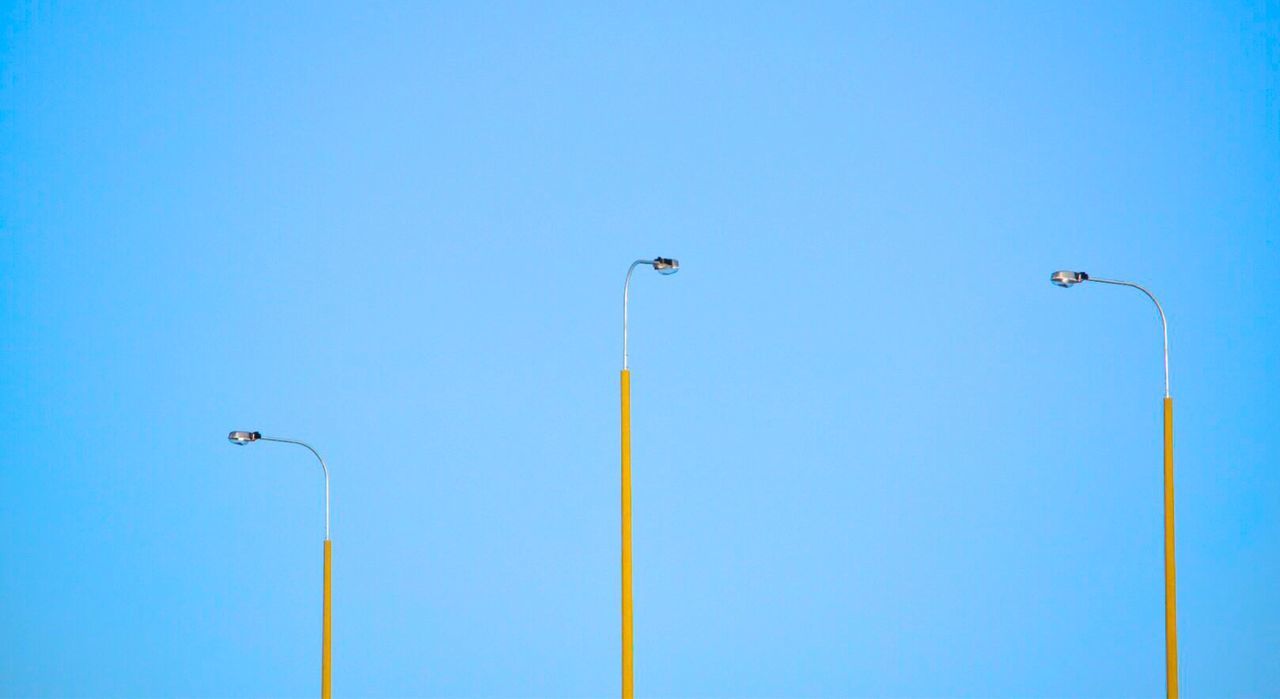 LOW ANGLE VIEW OF STREET LIGHTS AGAINST CLEAR BLUE SKY