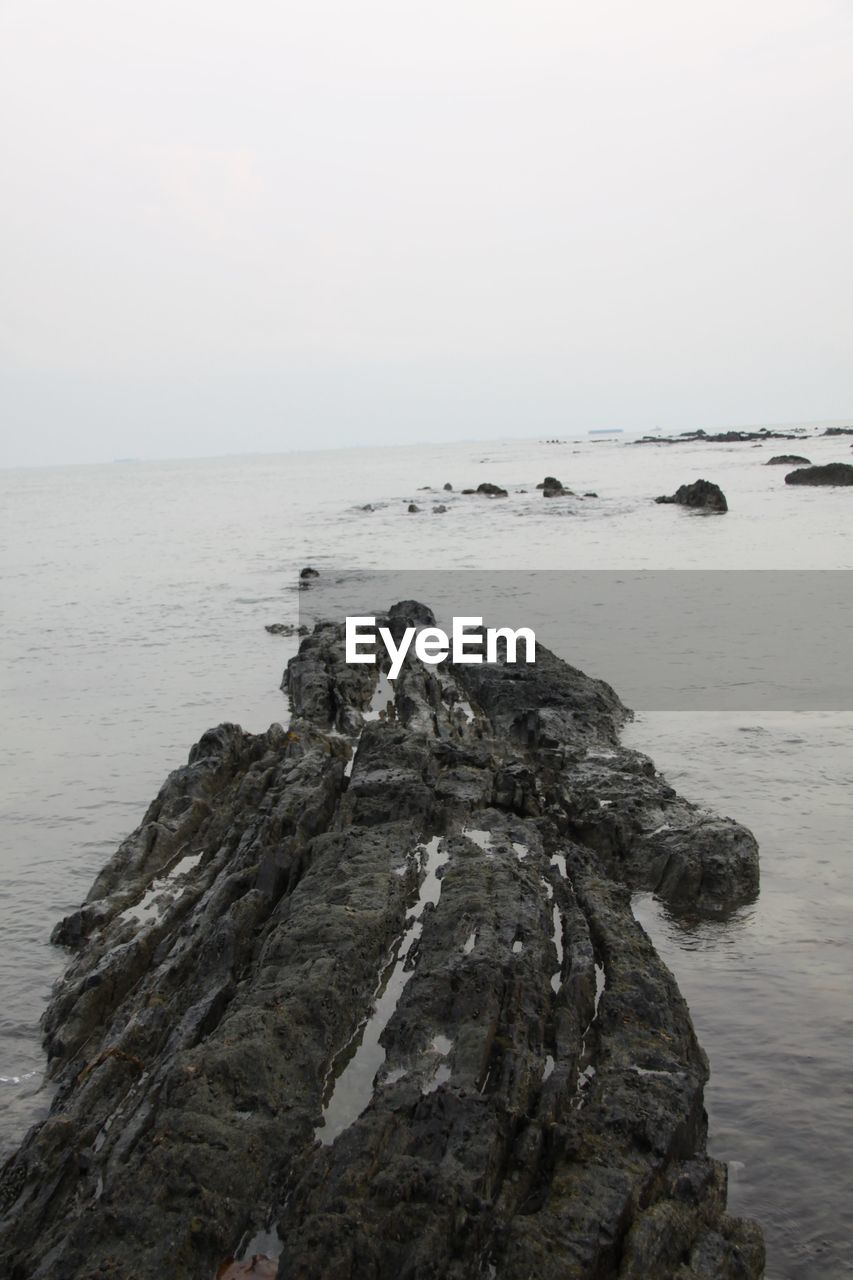 ROCK FORMATION AT SEA AGAINST CLEAR SKY