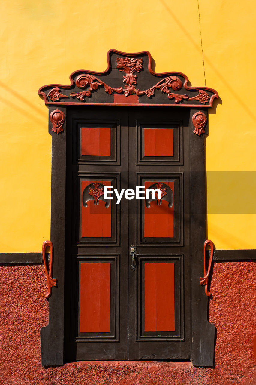 red, architecture, door, entrance, building exterior, built structure, no people, wall - building feature, building, closed, furniture, wood, house, protection, security, yellow, iron, residential district, day, orange color, outdoors, ornate