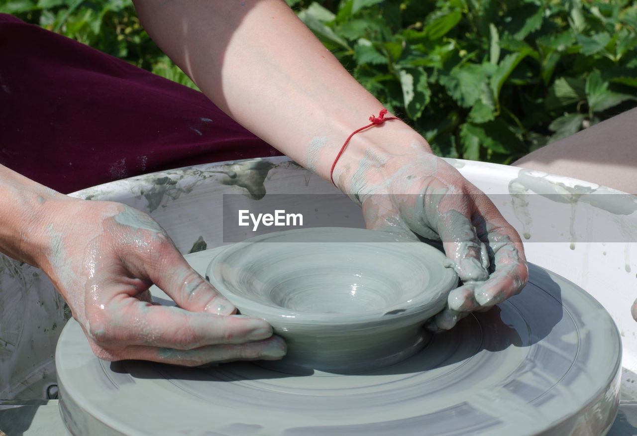 Ceramic workshop - the girl makes a pot of clay on a potter's wheel. hands closeup.