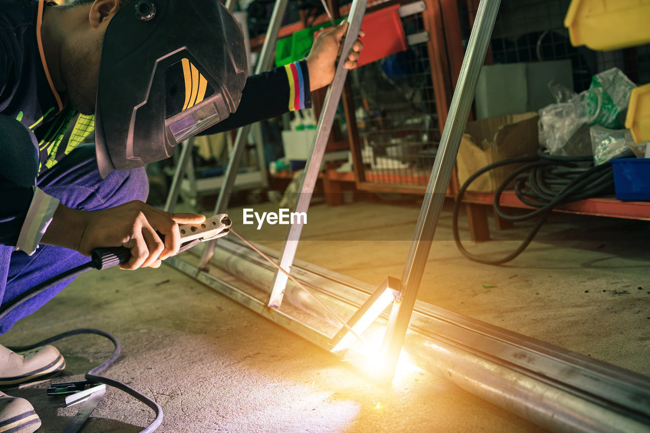 Asian welders wear protective masks and use industrial construction tools.