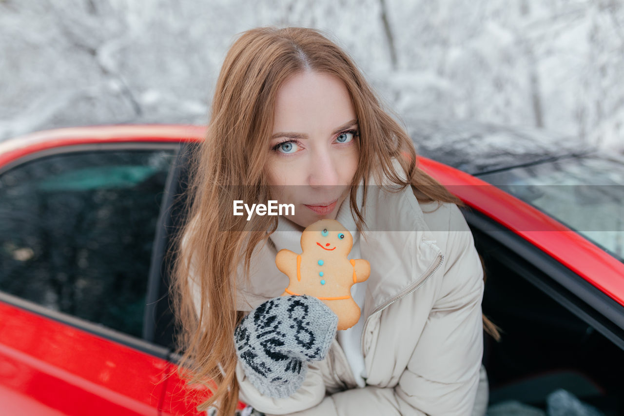Portrait of beautiful woman holding cookie in car