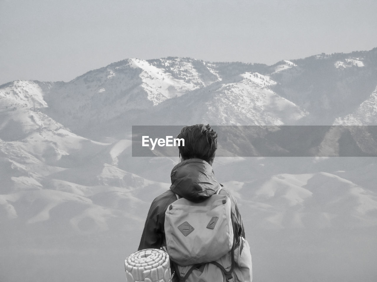 Rear view of man standing by mountain against sky