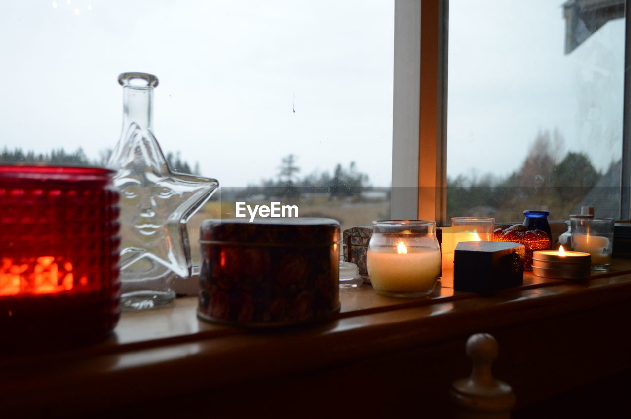 CLOSE-UP OF TEA LIGHT CANDLES ON GLASS TABLE