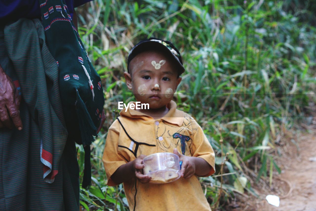 Portrait of boy with traditional face painting sanding on field