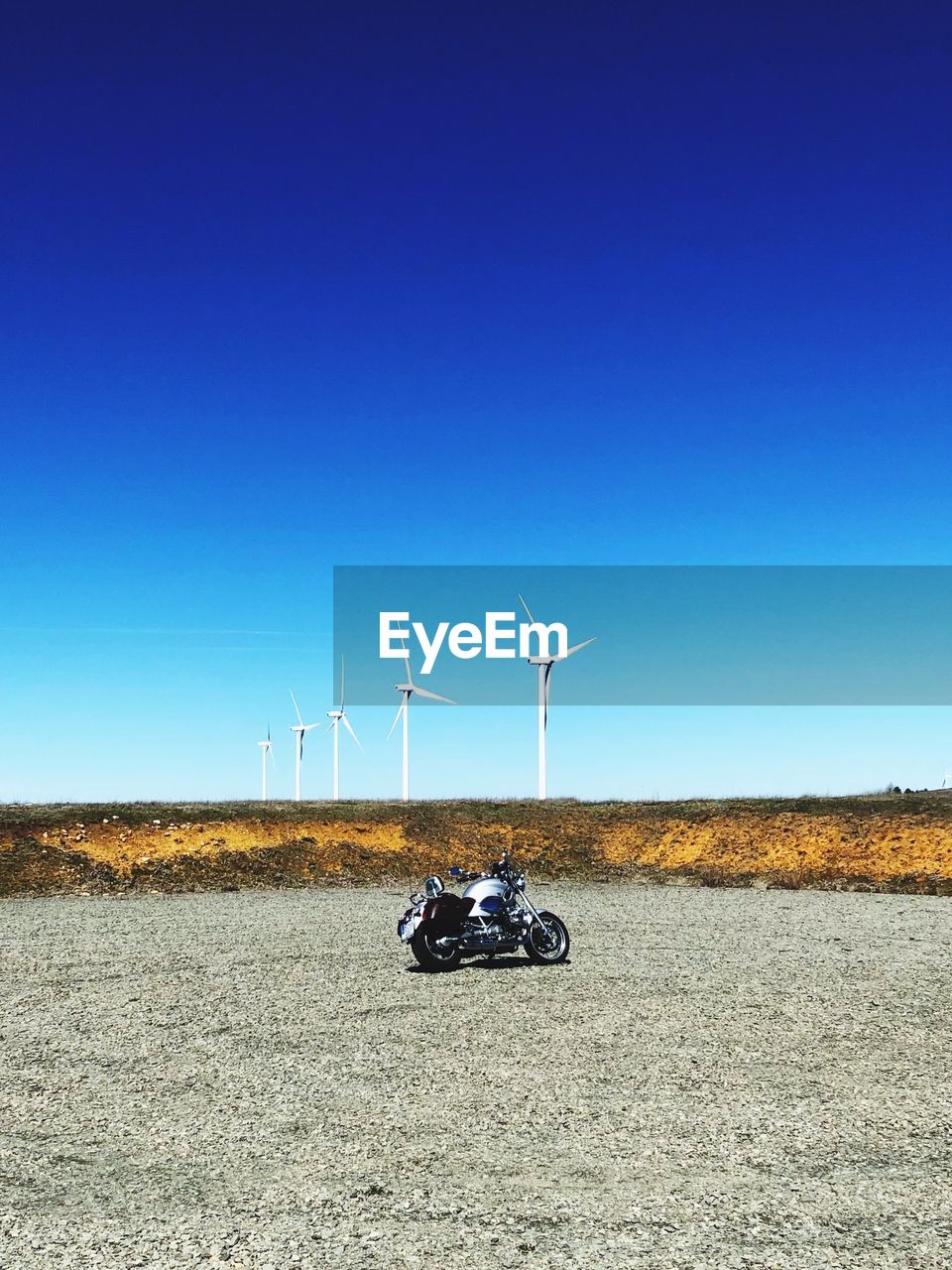 Windmill on field against clear blue sky