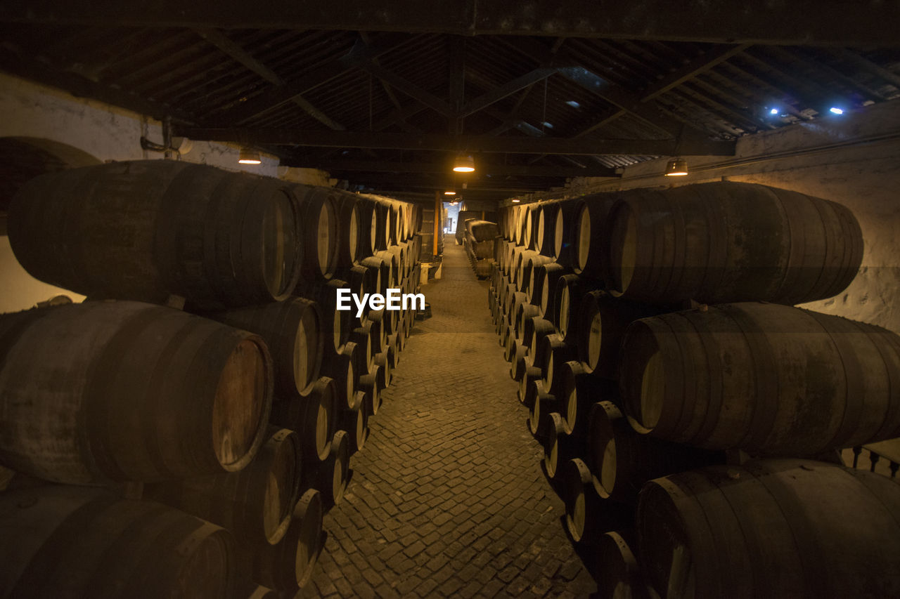 Stacked barrels arranged in illuminated warehouse