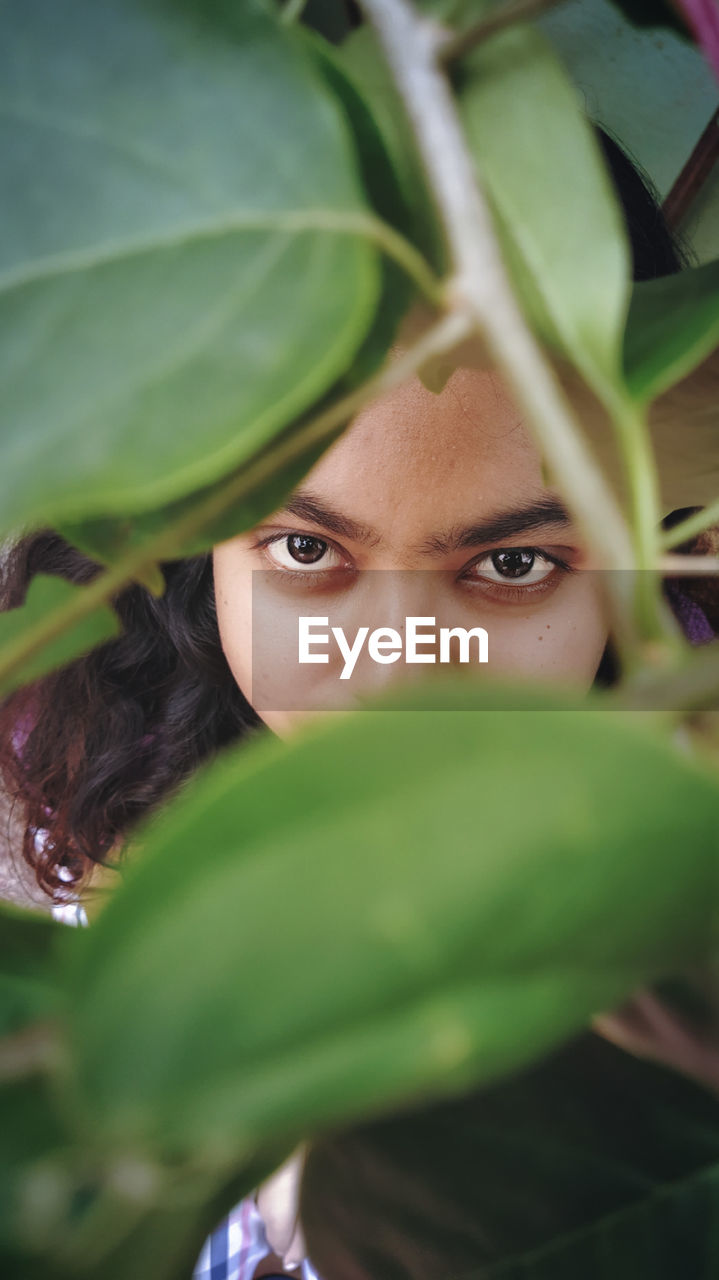 Close-up portrait of young woman amidst plant