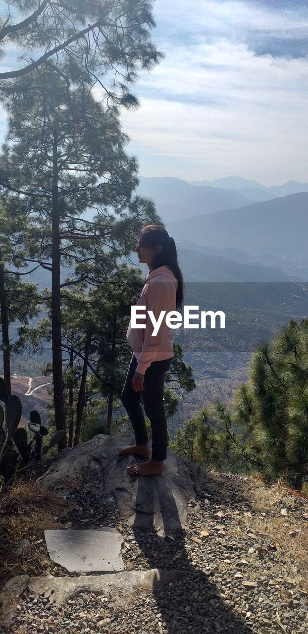 Woman standing on mountain against sky