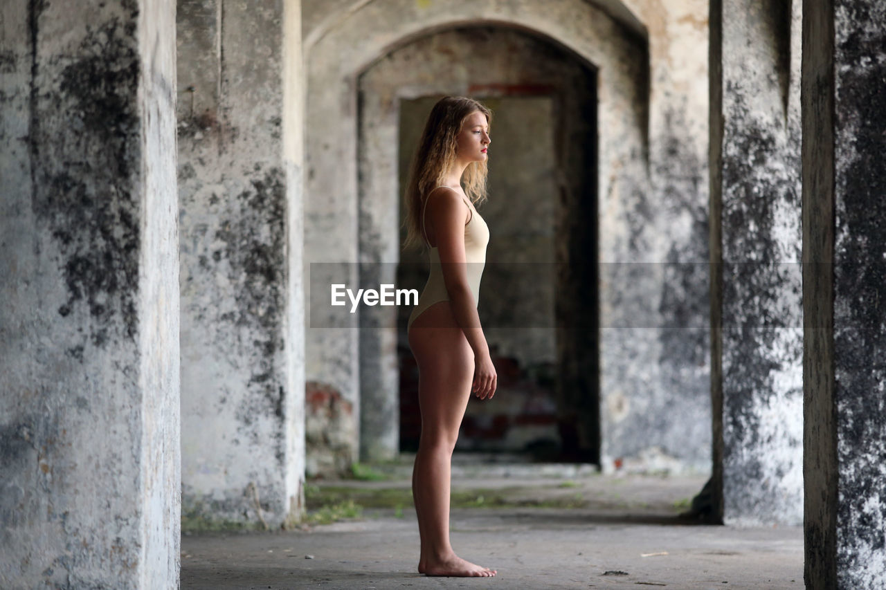 WOMAN STANDING IN FRONT OF WINDOW