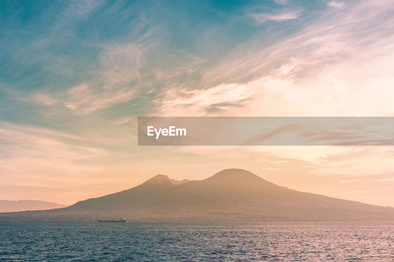 Scenic view of sea and volcano against sky