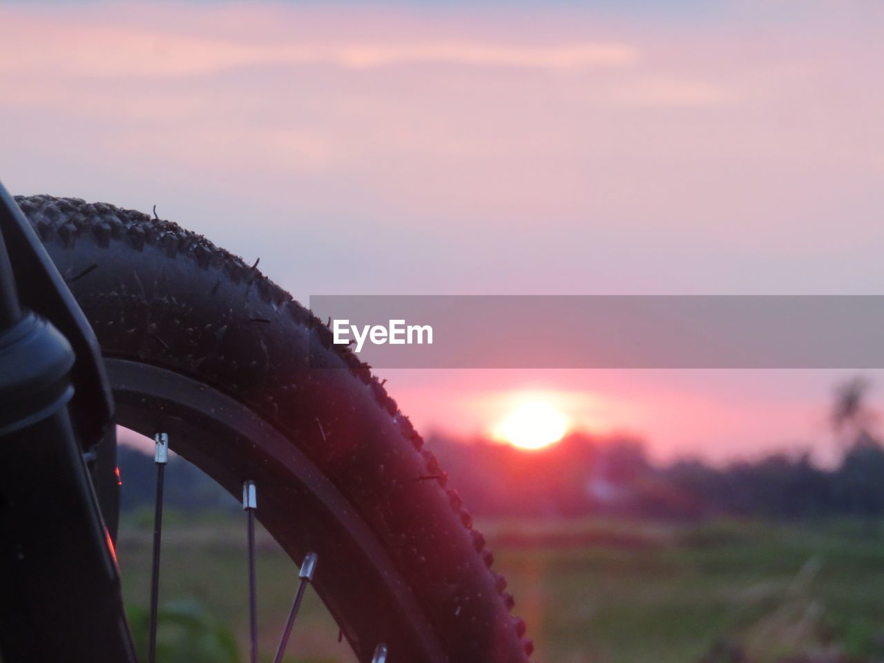 CLOSE-UP OF TIRE AGAINST SUNSET SKY
