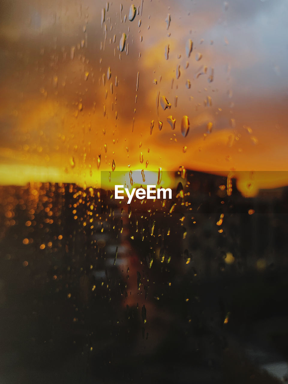 CLOSE-UP OF RAINDROPS ON GLASS WINDOW DURING SUNSET