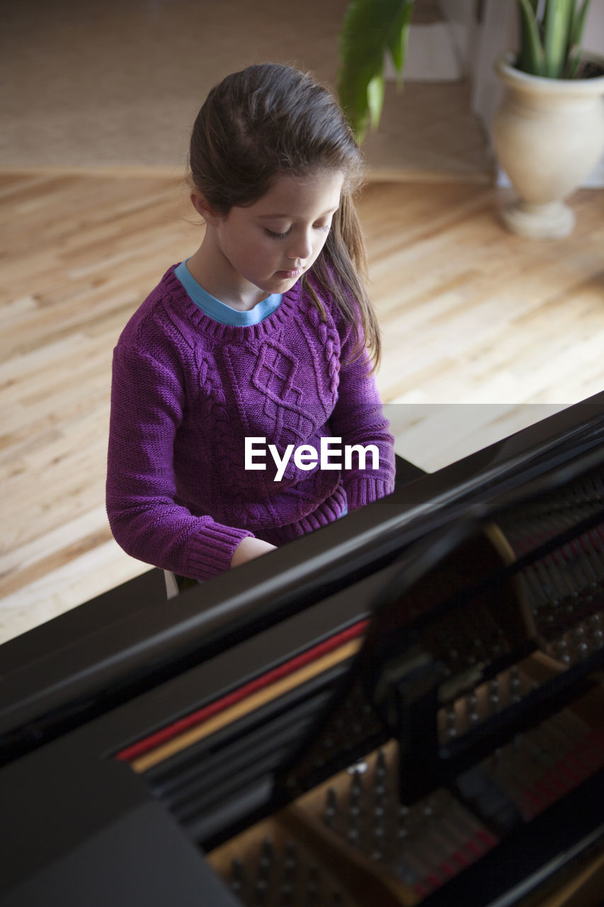 High angle view of girl playing piano at home