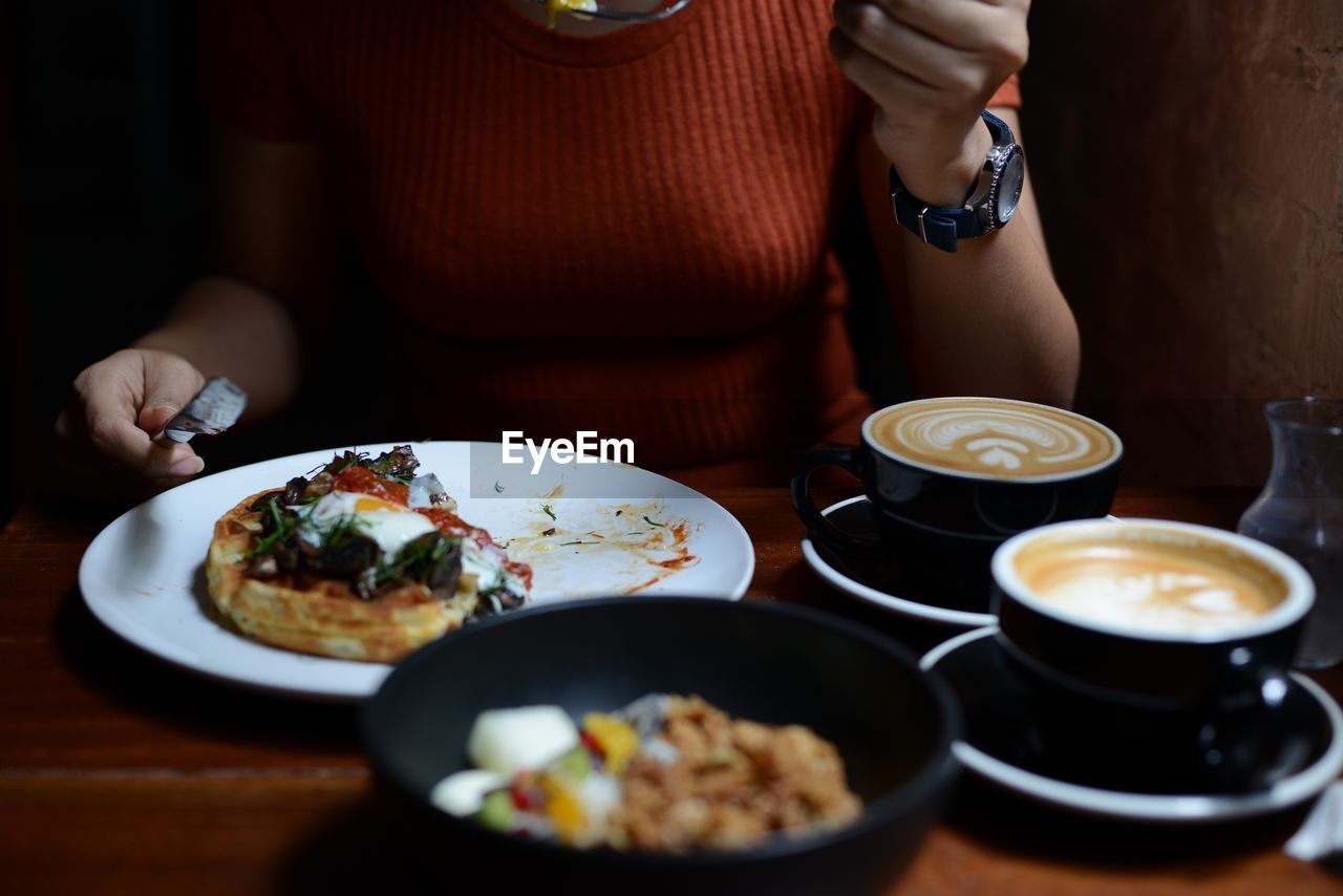 Midsection of woman holding food served on table