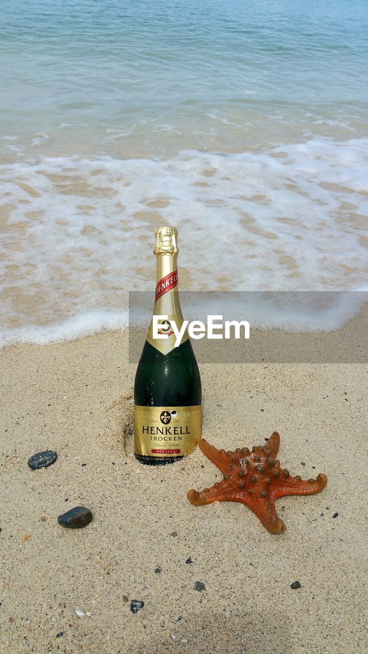 HIGH ANGLE VIEW OF WINE BOTTLE ON BEACH