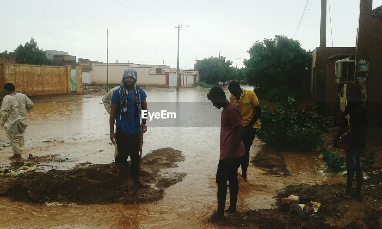 group of people, nature, men, occupation, full length, adult, dirt, sky, water, soil, architecture, working, tree, social issues, wet, plant, day, outdoors, city, mud, environment