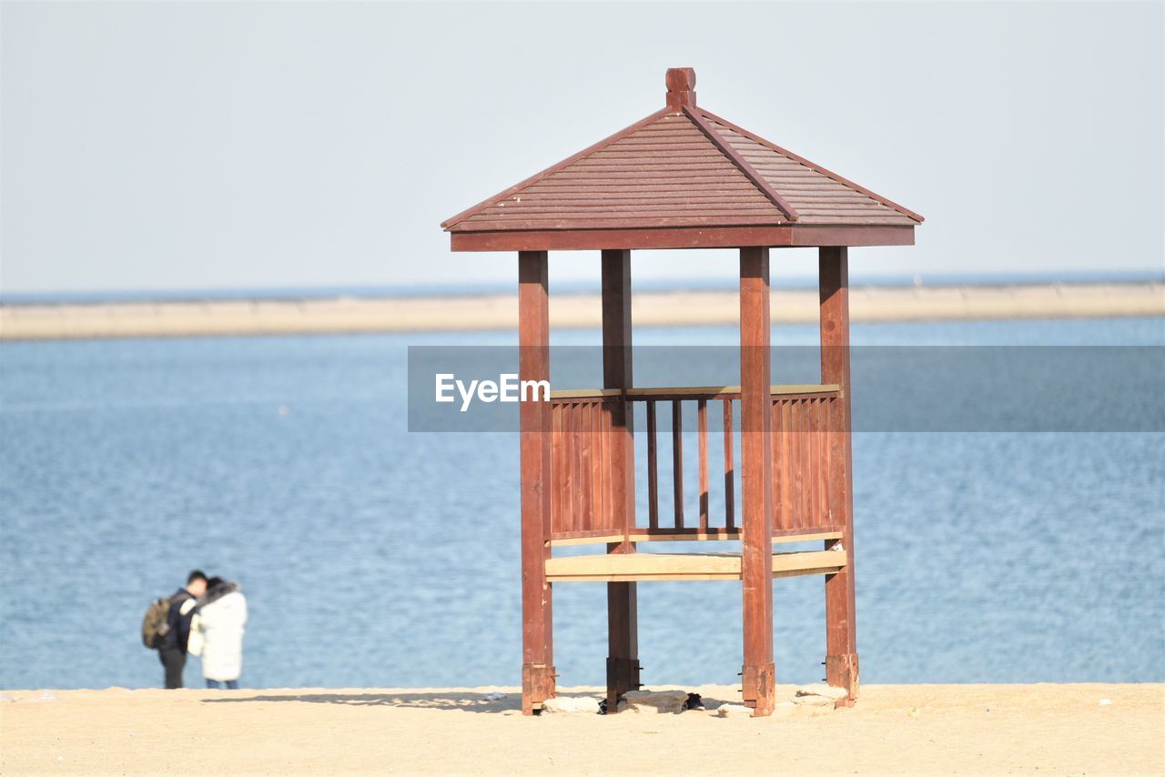 MAN ON BEACH AGAINST CLEAR SKY