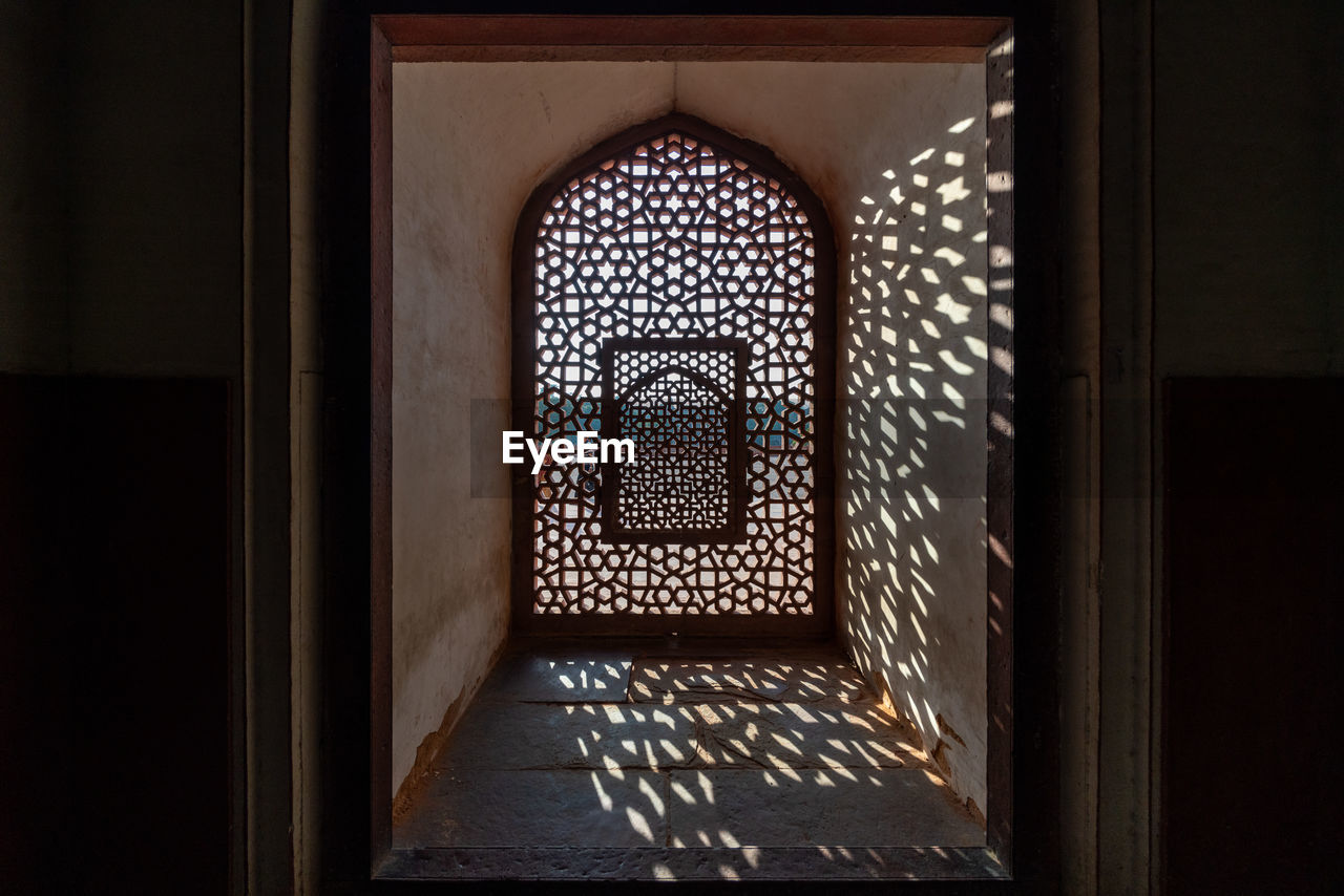 An patterned window casts elaborate shadows inside humayun's tomb, a landmark in delhi, india