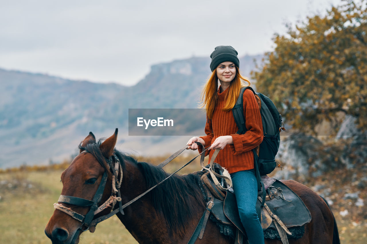 PORTRAIT OF YOUNG WOMAN RIDING HORSE IN A PEN