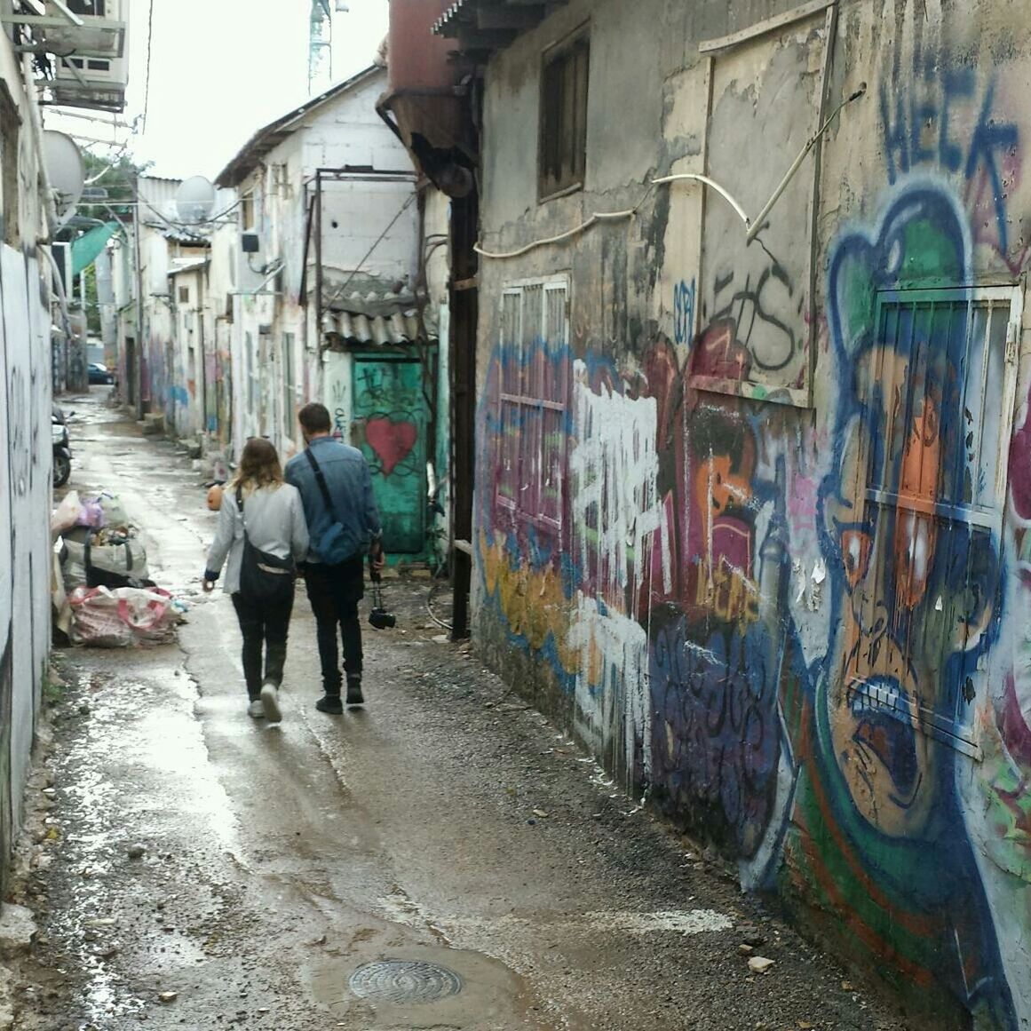 Rear view of people walking in alley amidst houses