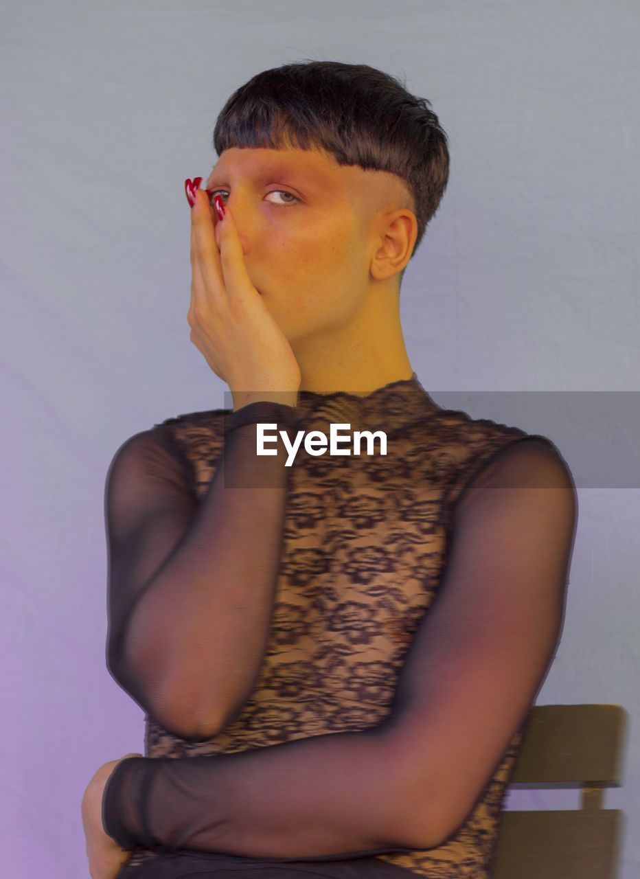 YOUNG WOMAN LOOKING AWAY AGAINST WHITE BACKGROUND