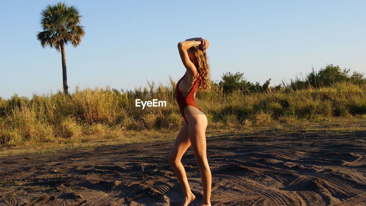 Full length of sensuous young woman wearing one piece swimsuit on sand