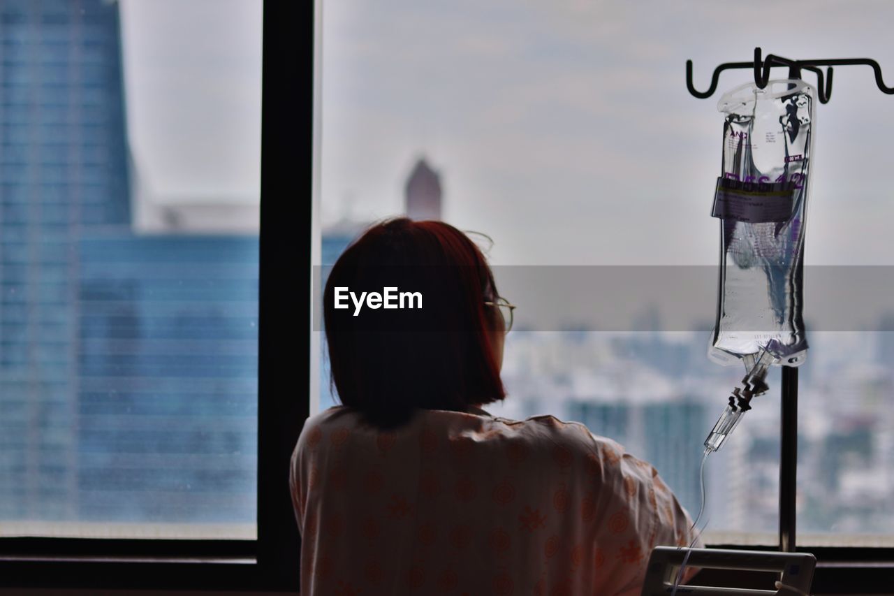 Rear view of man looking through window