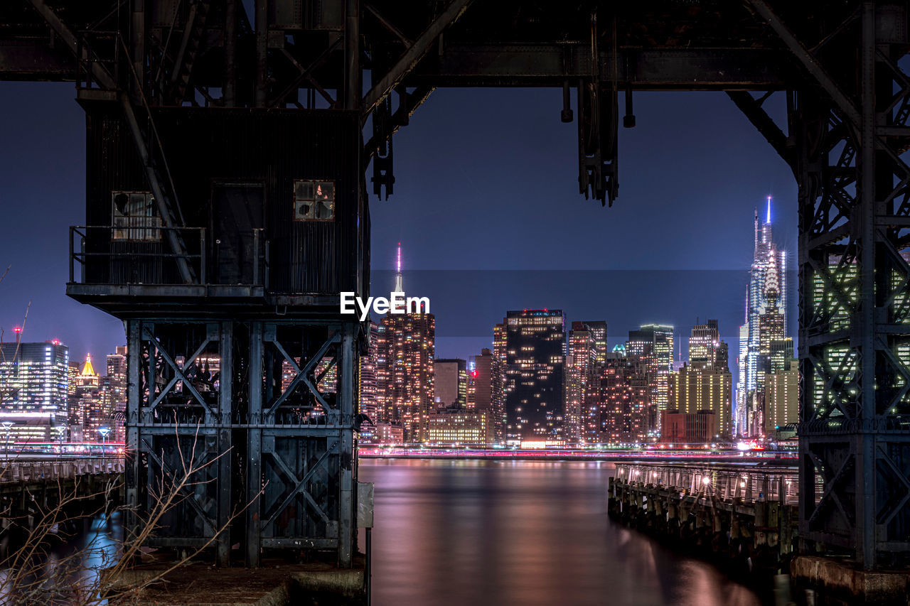 Old railway crane over east river in queens, new york at night