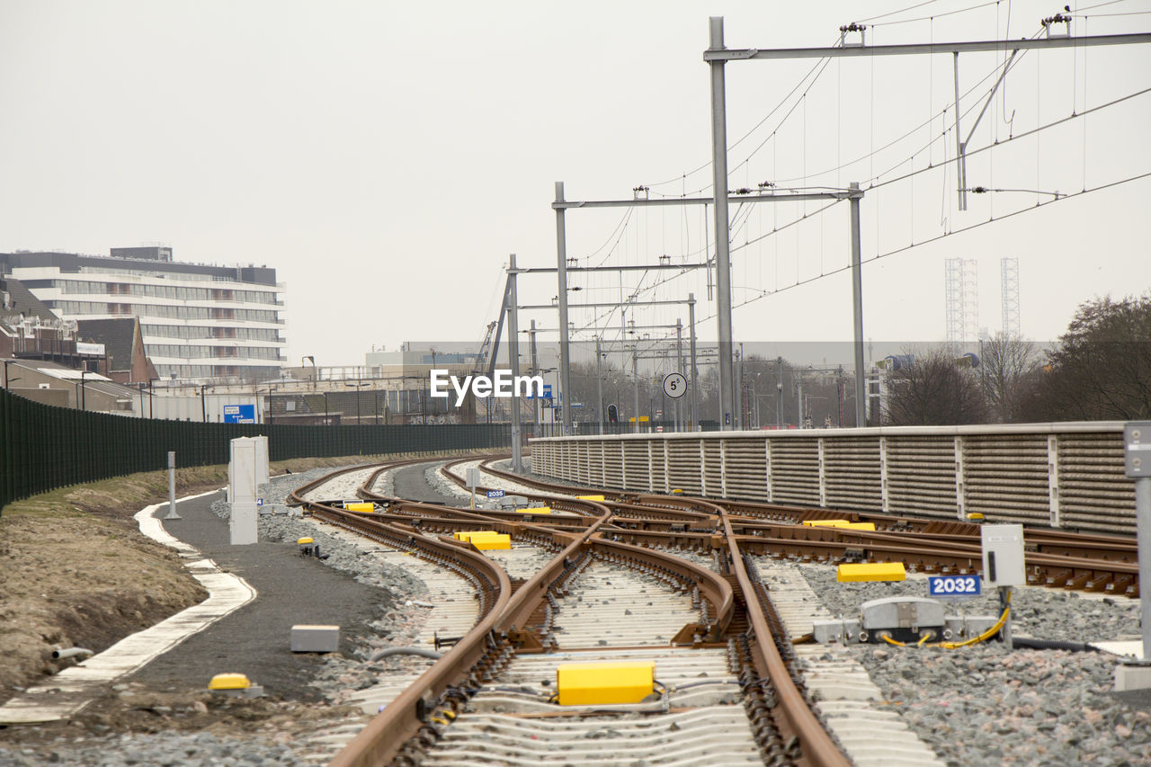 Railroad tracks in city against clear sky