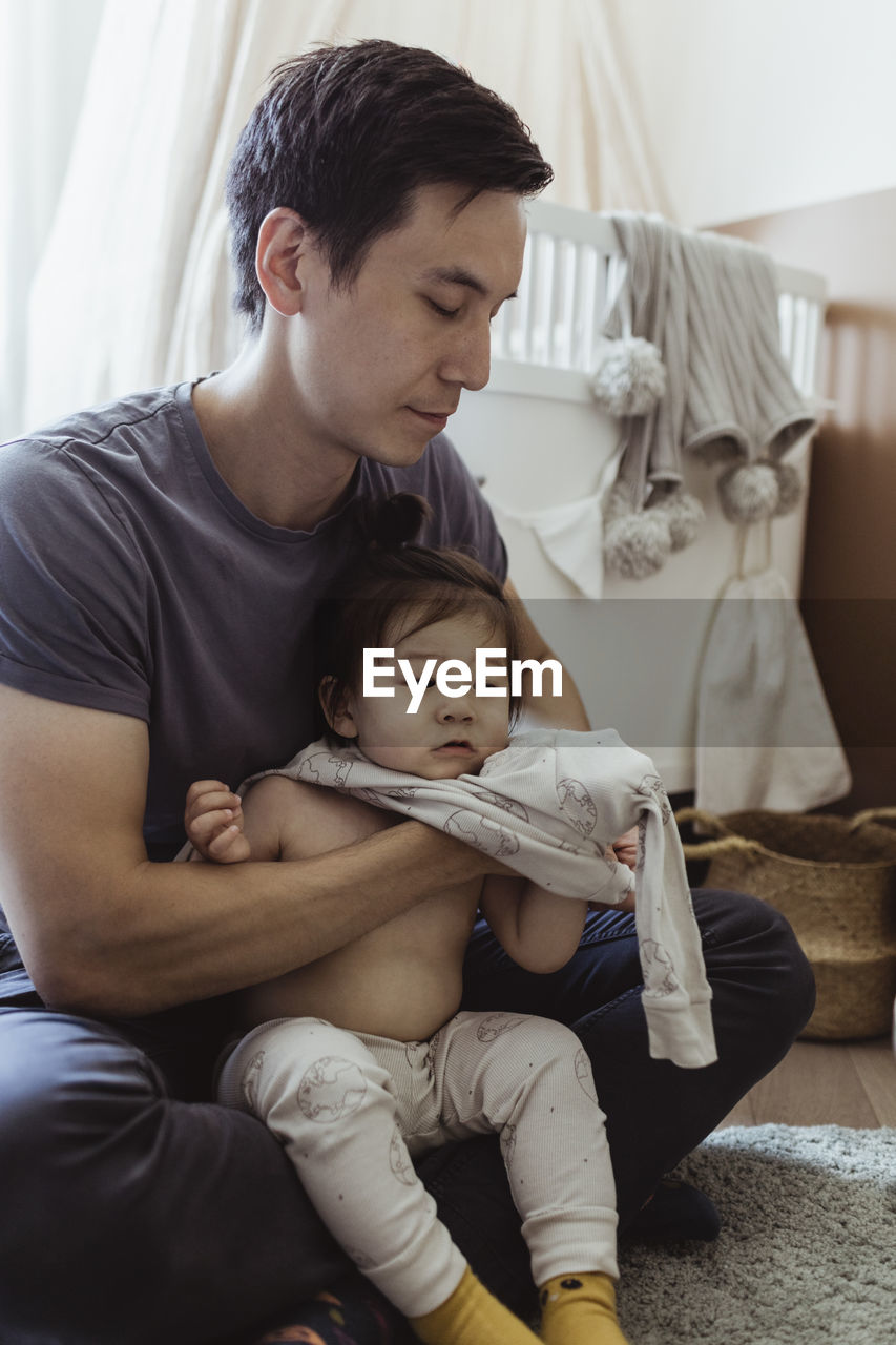 Father changing clothes of baby son at home