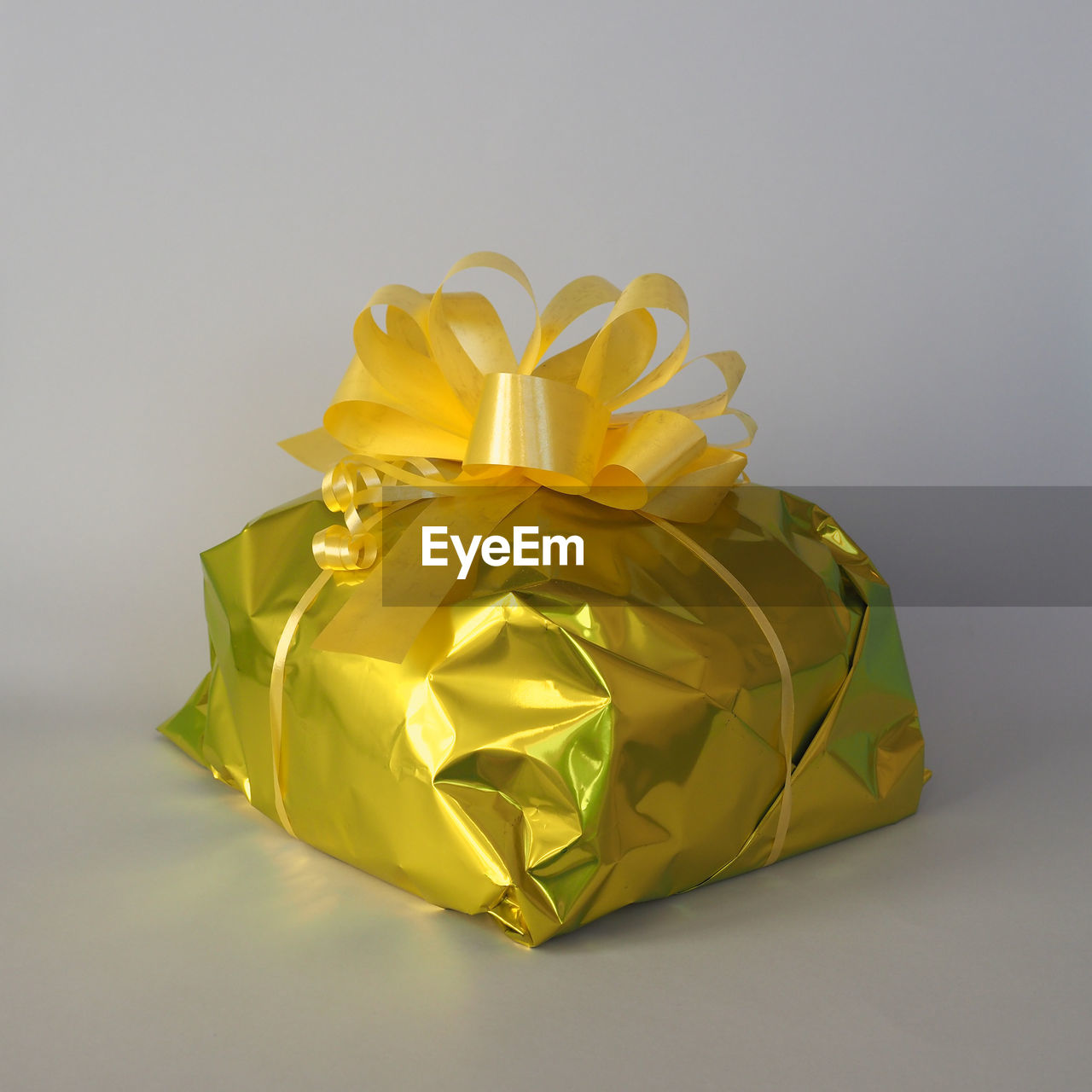 yellow, studio shot, gift, gold, art, paper, indoors, gray background, celebration, petal, ribbon, single object, flower, no people, surprise, origami paper, wrapping paper, gray, origami, wrapped, bow, wealth, cut out, copy space, shiny, emotion, holiday, tied bow, box, gift box, still life, event, luxury