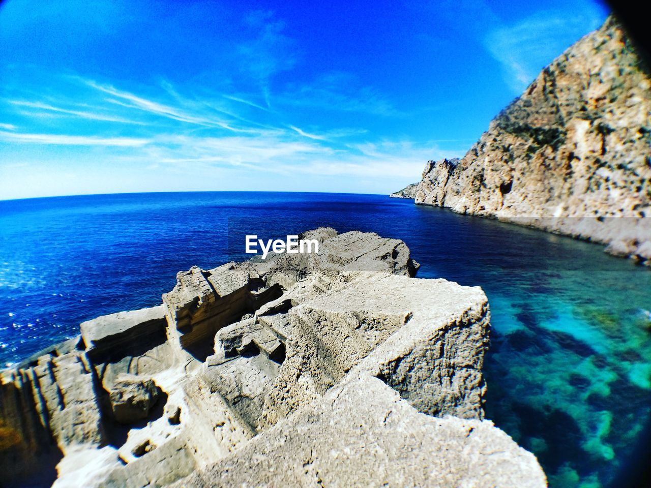 Rock formations by sea against blue sky