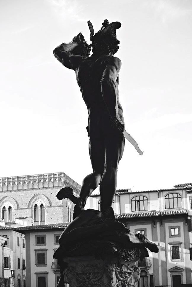 LOW ANGLE VIEW OF WOMAN STANDING AGAINST SKY