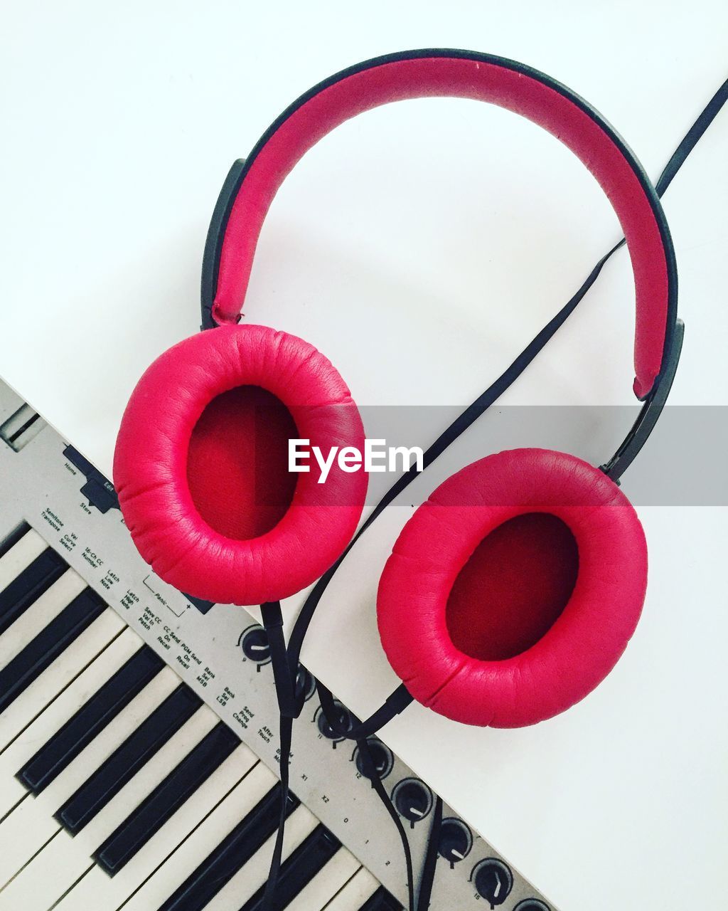 Directly above shot of pink headphones and piano on white background