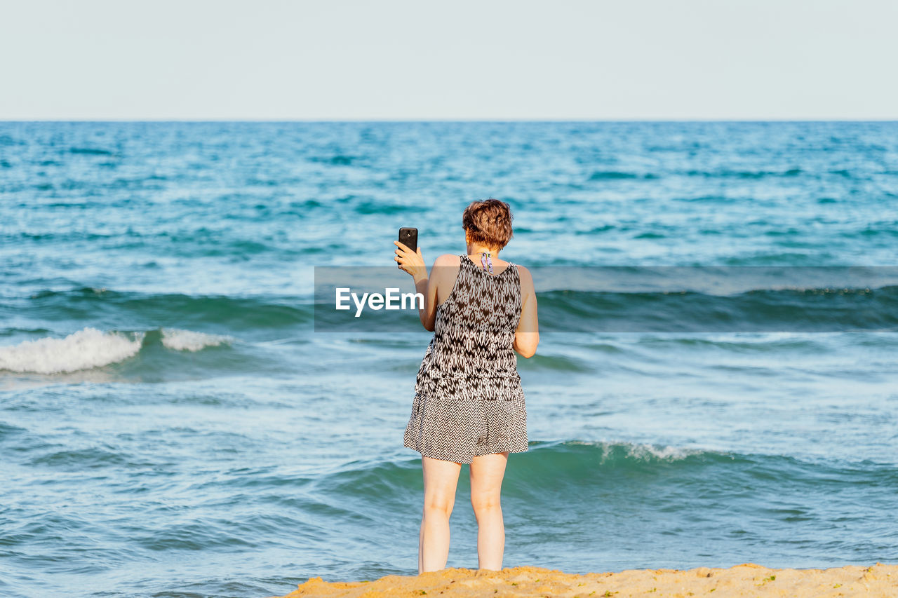 FULL LENGTH OF MAN STANDING ON BEACH