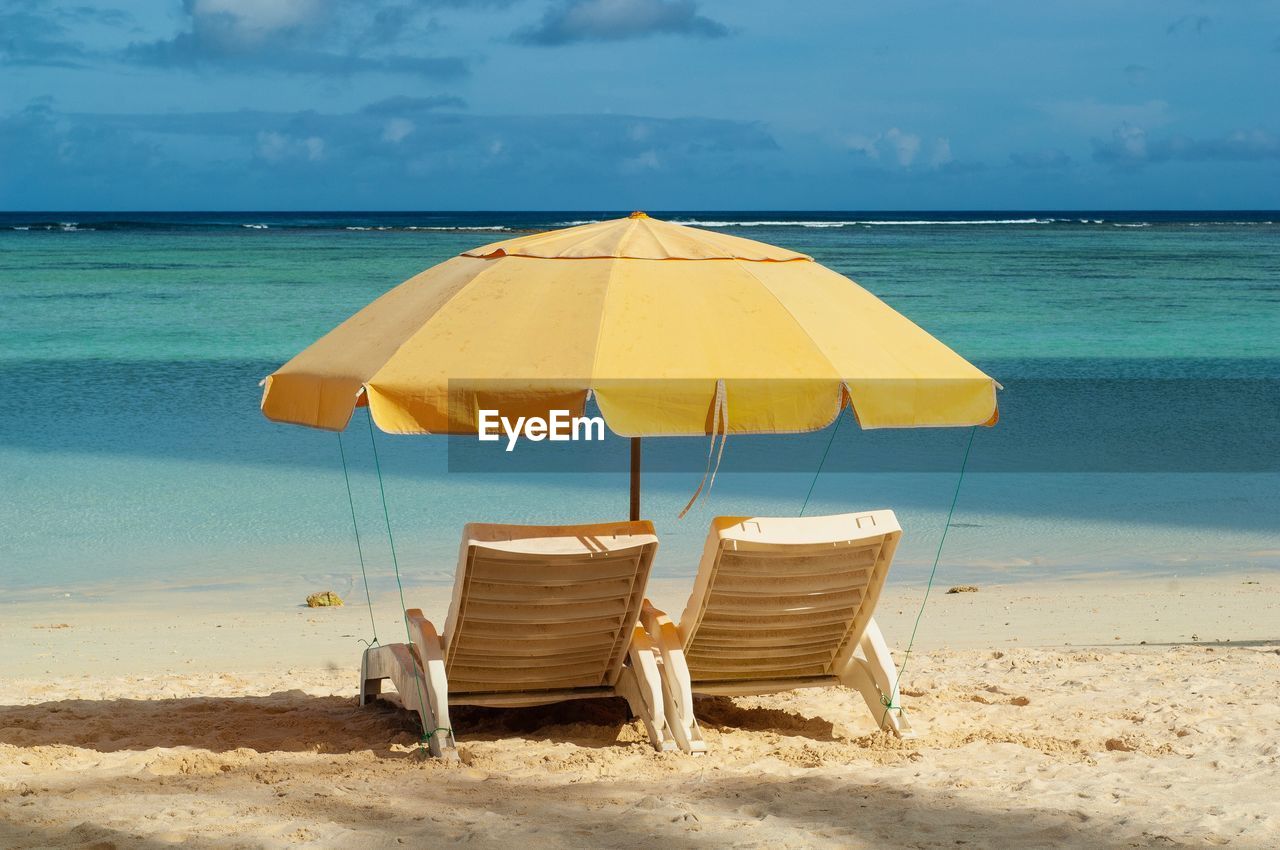 DECK CHAIRS ON BEACH AGAINST SEA