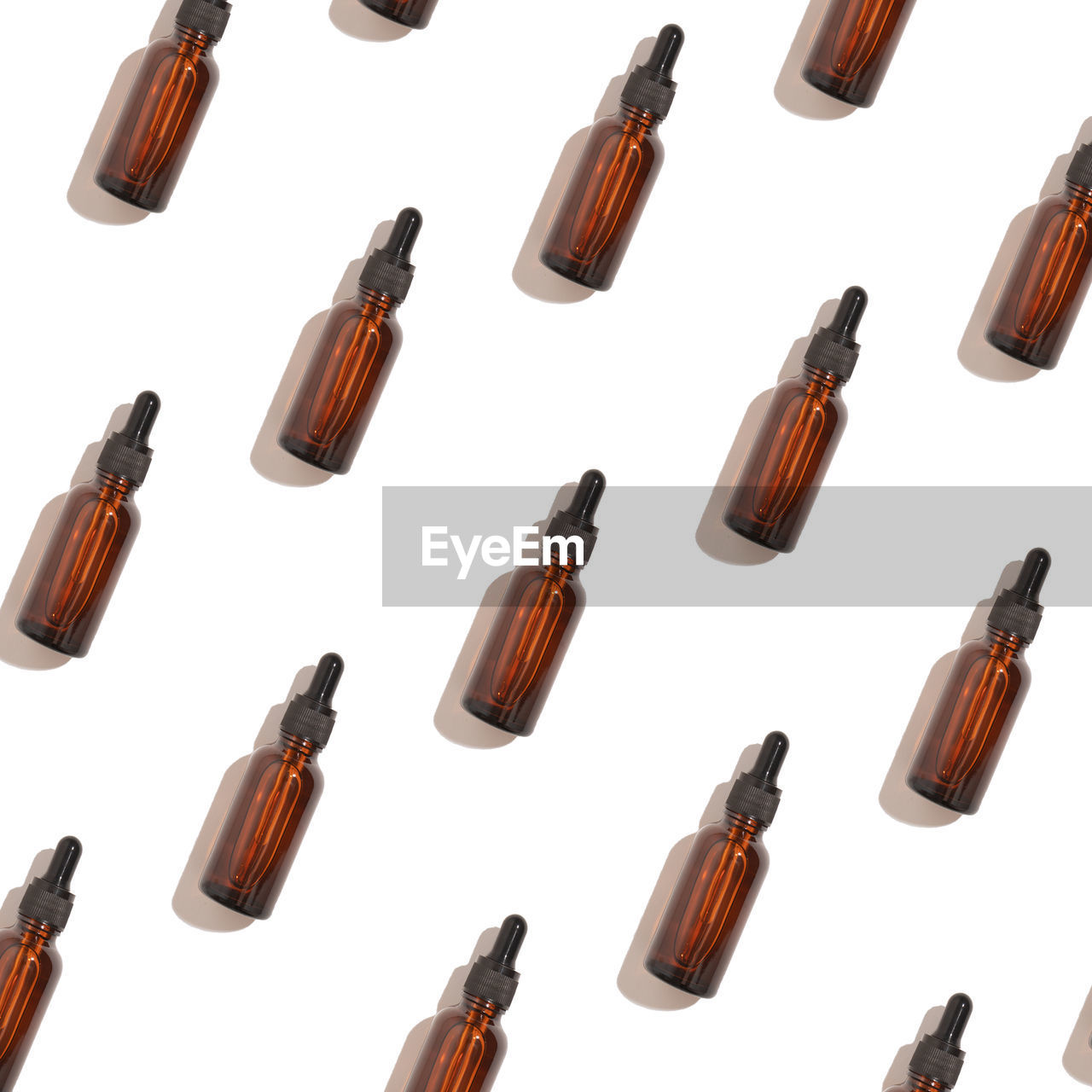 Seamless pattern of anti aging serum in glass bottle with dropper on white background.
