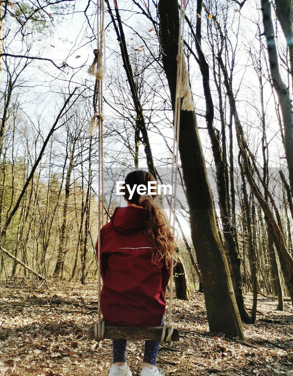 REAR VIEW OF WOMAN WITH UMBRELLA WALKING ON BARE TREES