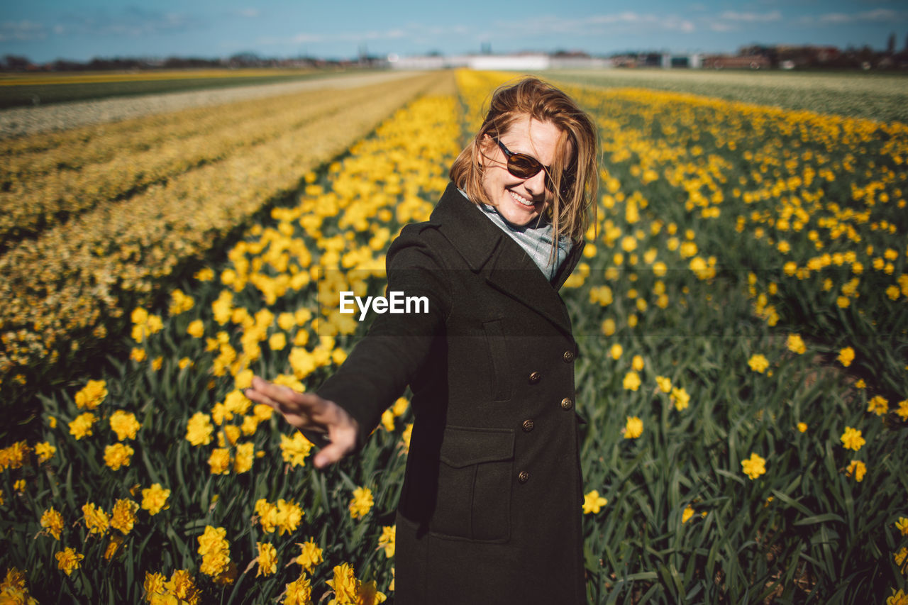 Woman standing on yellow narcissus flower field