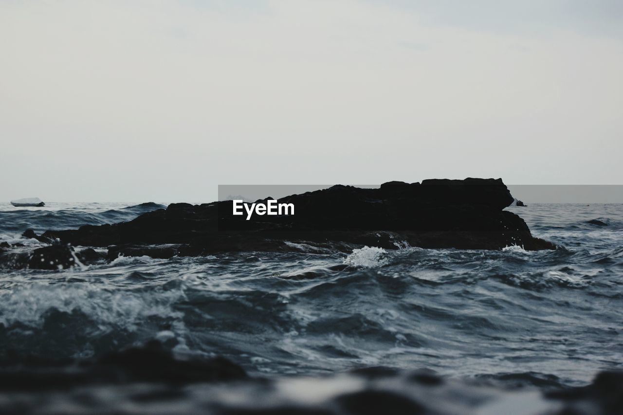 Rocks amidst sea against clear sky