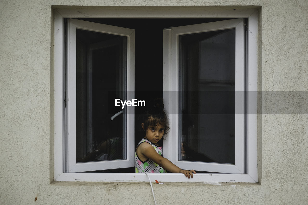 GIRL LOOKING THROUGH WINDOW IN ROOM