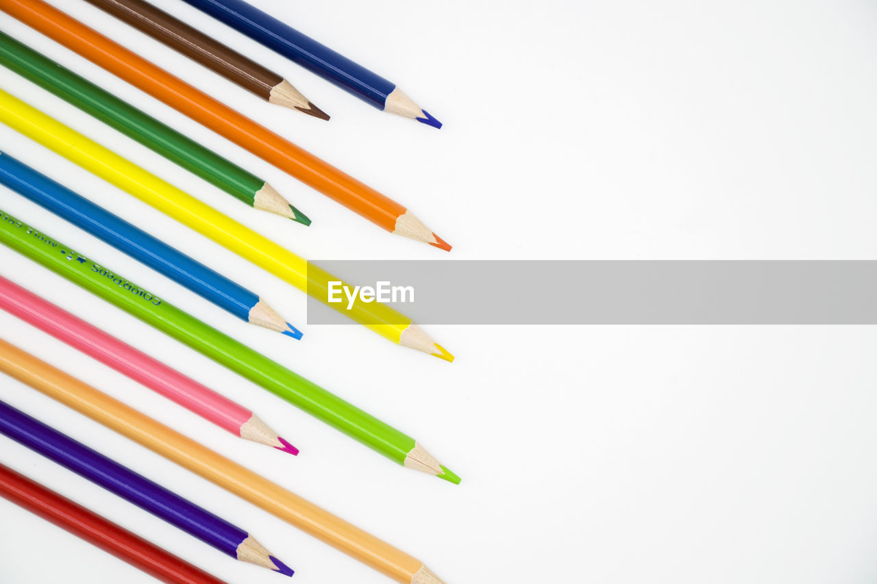 CLOSE-UP OF COLORED PENCILS AGAINST WHITE BACKGROUND