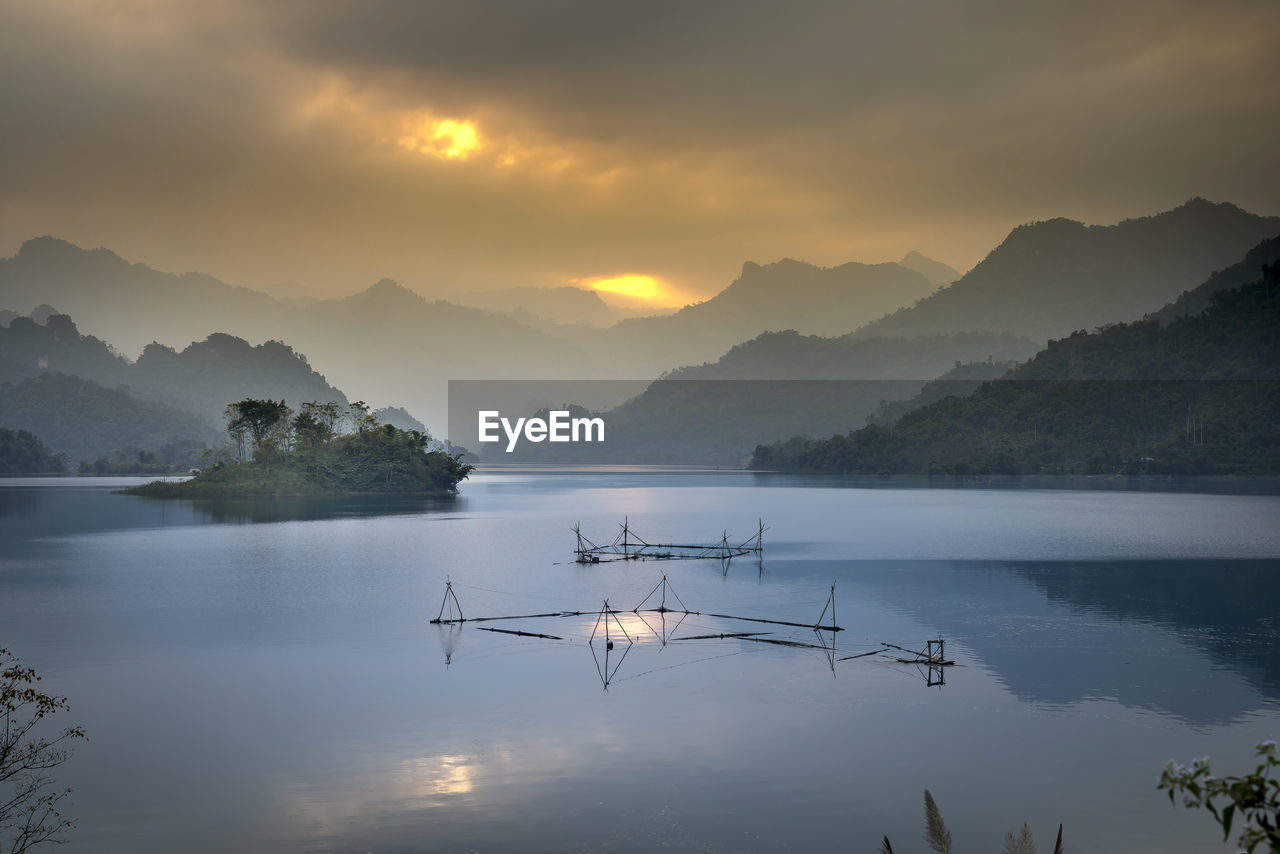 Scenic view of lake by mountains against sky during sunset