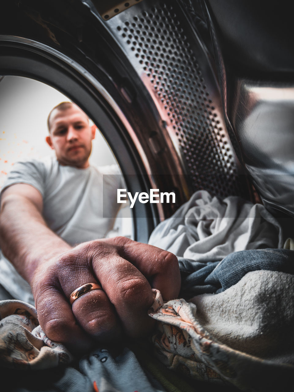 Low angle view of man putting garments in washing machine